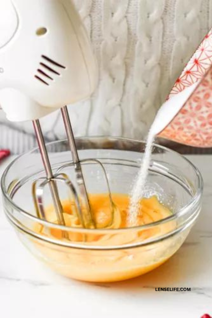 adding sugar to the egg yolks in a pan